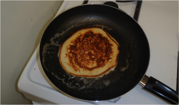 Pancake in frying pan after flipping, one side cooked