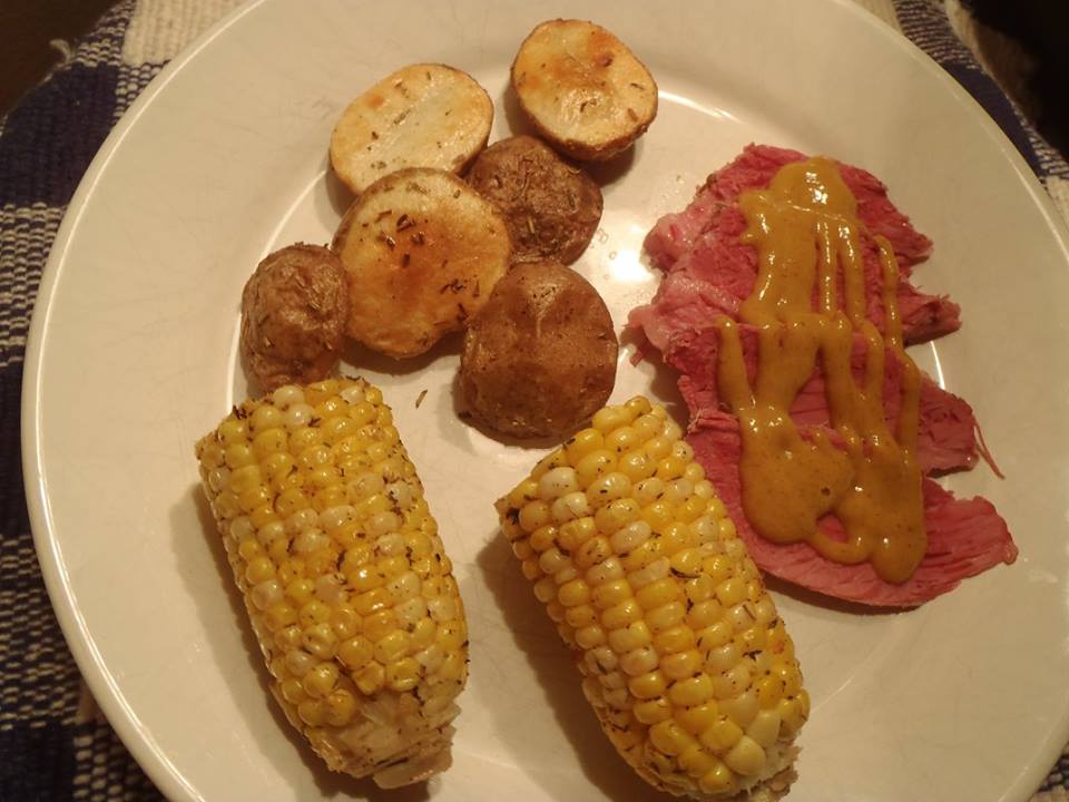 Picture Corned Beef Brisket Sliced and plated with potatoes and corn on the cob