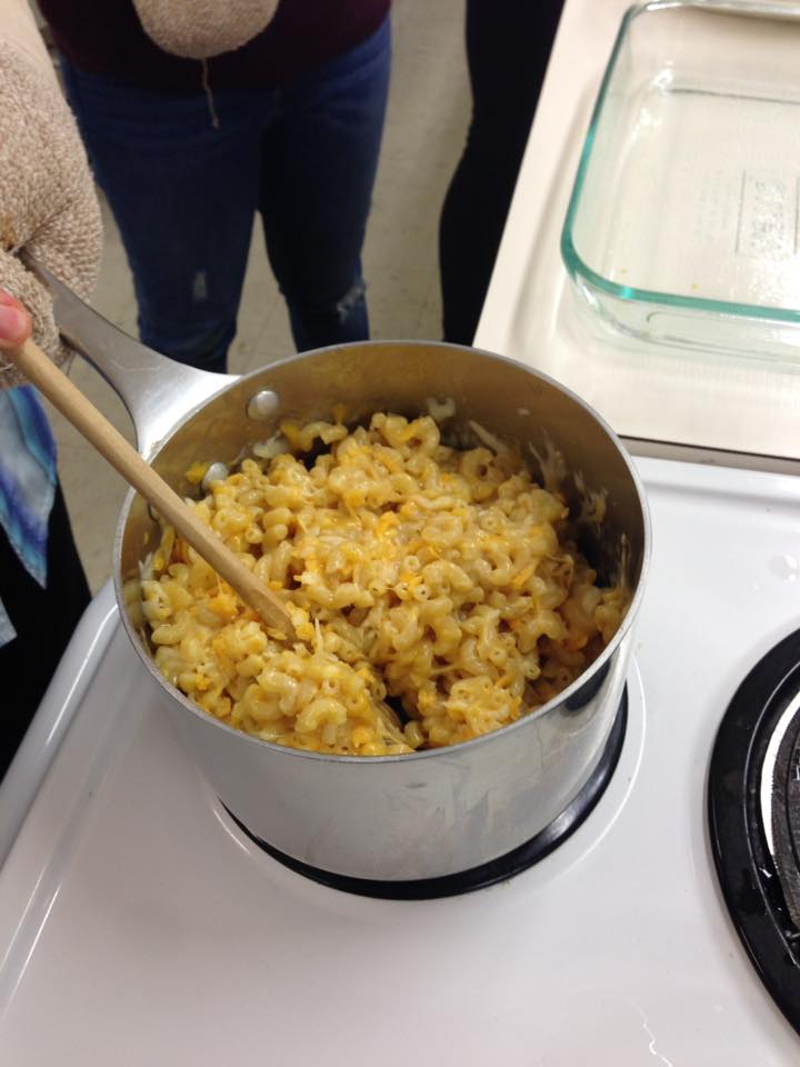 Cooked macaroni, half of the cheese and butter being stirred together