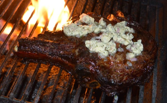 Steak topped with compound butter melting on the grill 